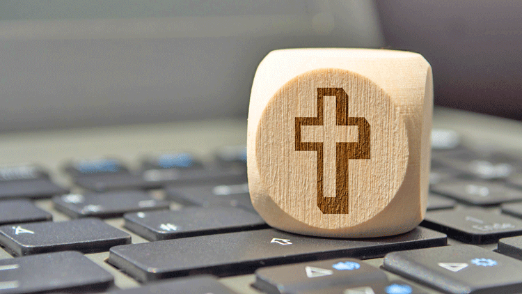 Holzwürfel mit christlichem Kreuzsymbol auf einer Computertastatur; Copyright Panthermedia