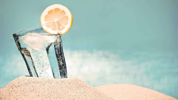 Glas Mineralwasser, Orangenscheibe im Sand, Copyright Panthermedia