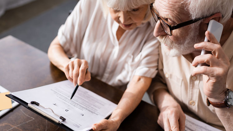 Älteres Paar blickt sorgenvoll auf ein Schreiben in der Hand der Frau, der Mann telefoniert; Copyright Panthermedia