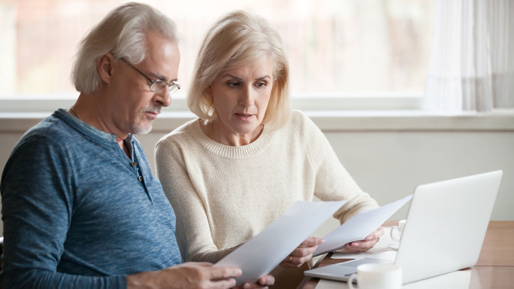 Älteres Paar sitzt mit Papieren in der Hand besorgt vor einem Laptop; Copyright Panthermedia