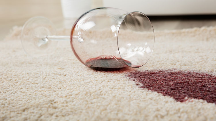 Rotweinglas, das auf einem hellen Teppich umgefallen ist und einen Fleck hinterlässt;Copyright Panthermedia
