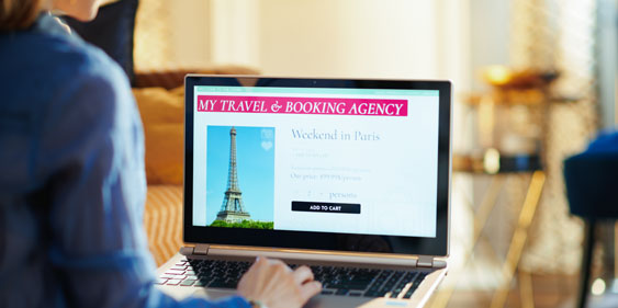 Zum Artikel "Gefälschte Reiseangebote im Internet"; Das Bild zeigt eine Frau vor einem Laptop, die eine Reise bucht