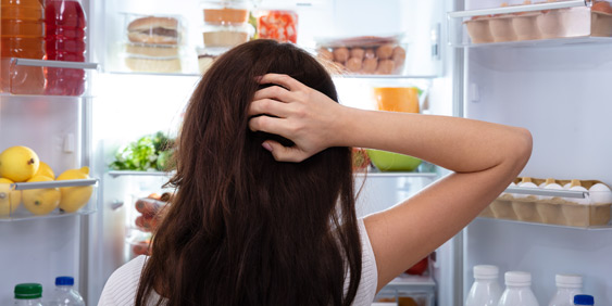Frau steht ratlos vor einem geöffneten Kühlschrank, Copyright Panthermedia