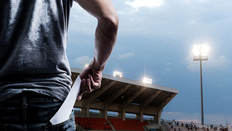 Das Bild zeigt einen Mann von hinten, der im Stadion ein Ticket aus seiner Gesäßtasche zieht; Copyright Fotolia