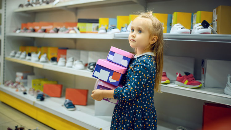 Das Bild zeigt ein minderjähriges Mädchen in einem Schuhladen, das drei Schuhkartons trägt; Copyright Panthermedia