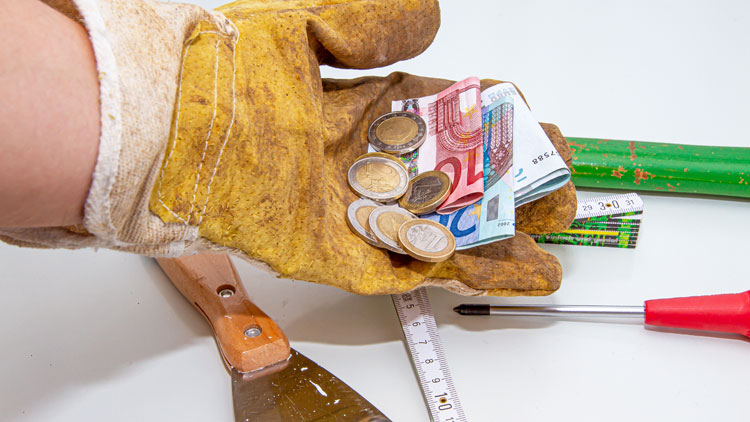 Werkzeuge und Handwerkerhand mit Arbeitshandschuh, die Geld hält; Copyright Panthermedia